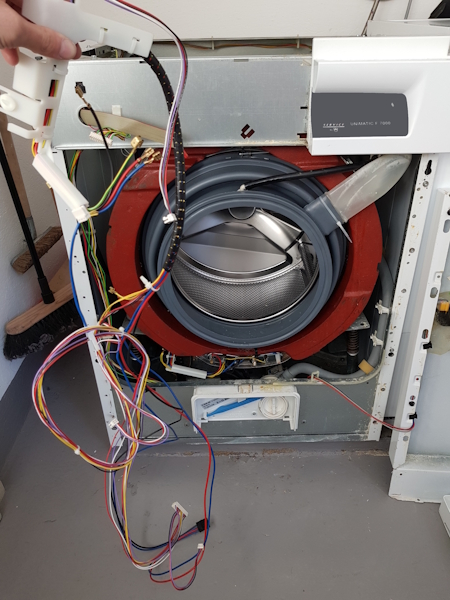 Geöffnete Waschmaschine mit freigelegter Verkabelung und Trommel während der Reparatur