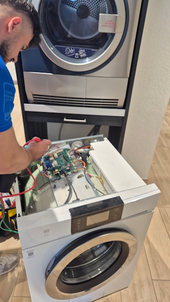Servicetechniker der ALB24 GmbH misst die Steuerelektronik einer geöffneten Waschmaschine durch