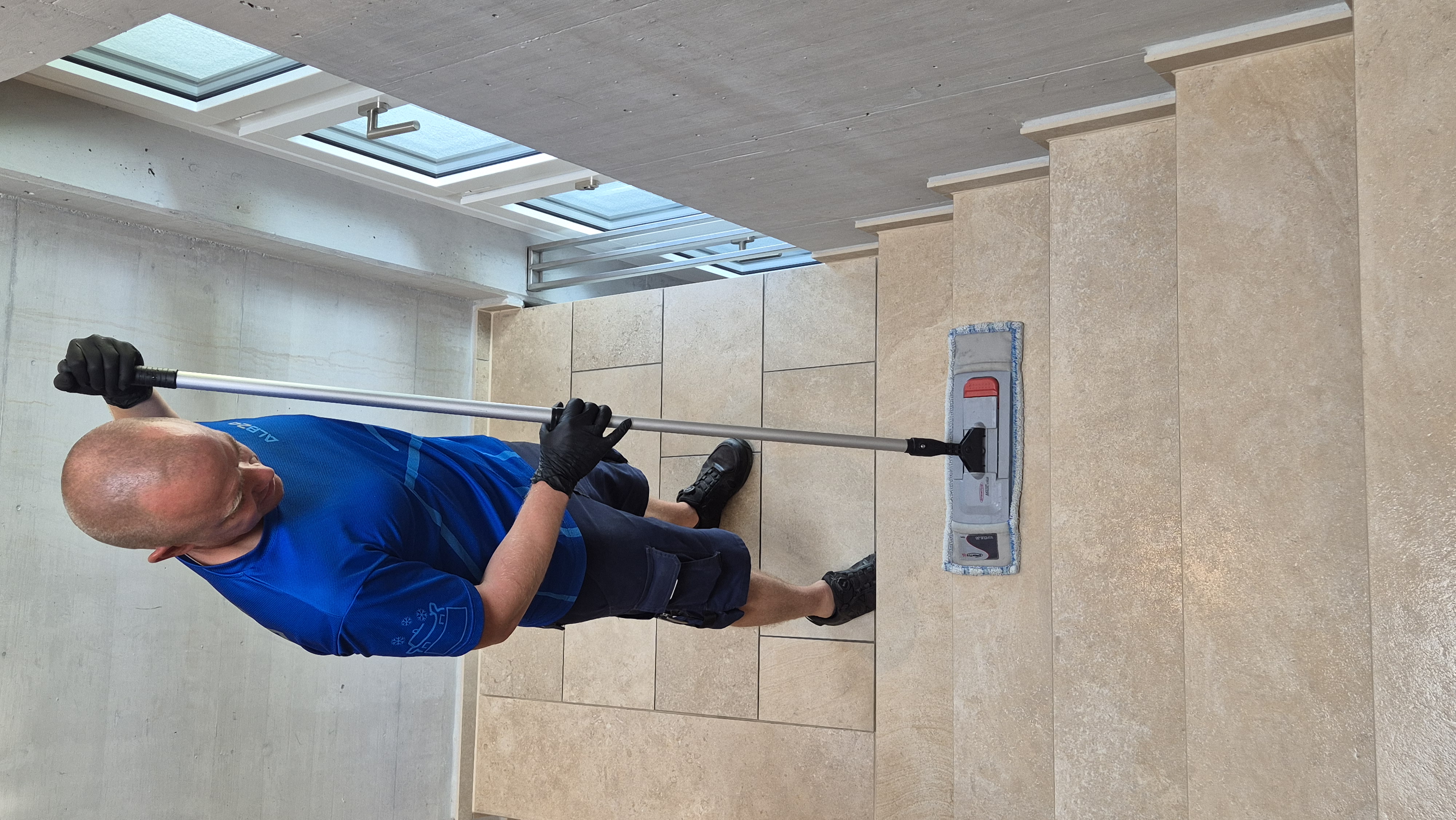 Mitarbeiter der ALB24 GmbH reinigt eine Treppe im Treppenhaus mit dem Wischmop