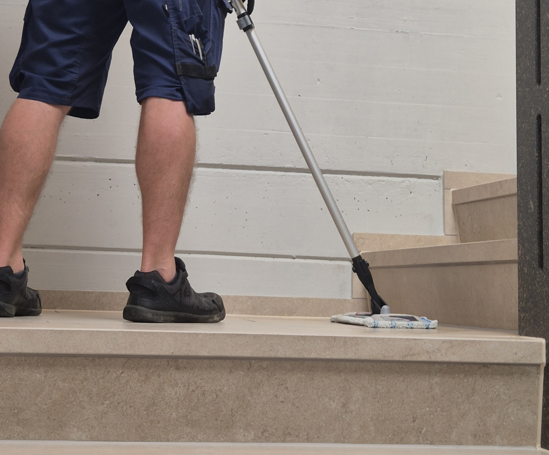 Mitarbeiter der ALB24 GmbH reinigt eine Treppe im Treppenhaus mit dem Wischmop