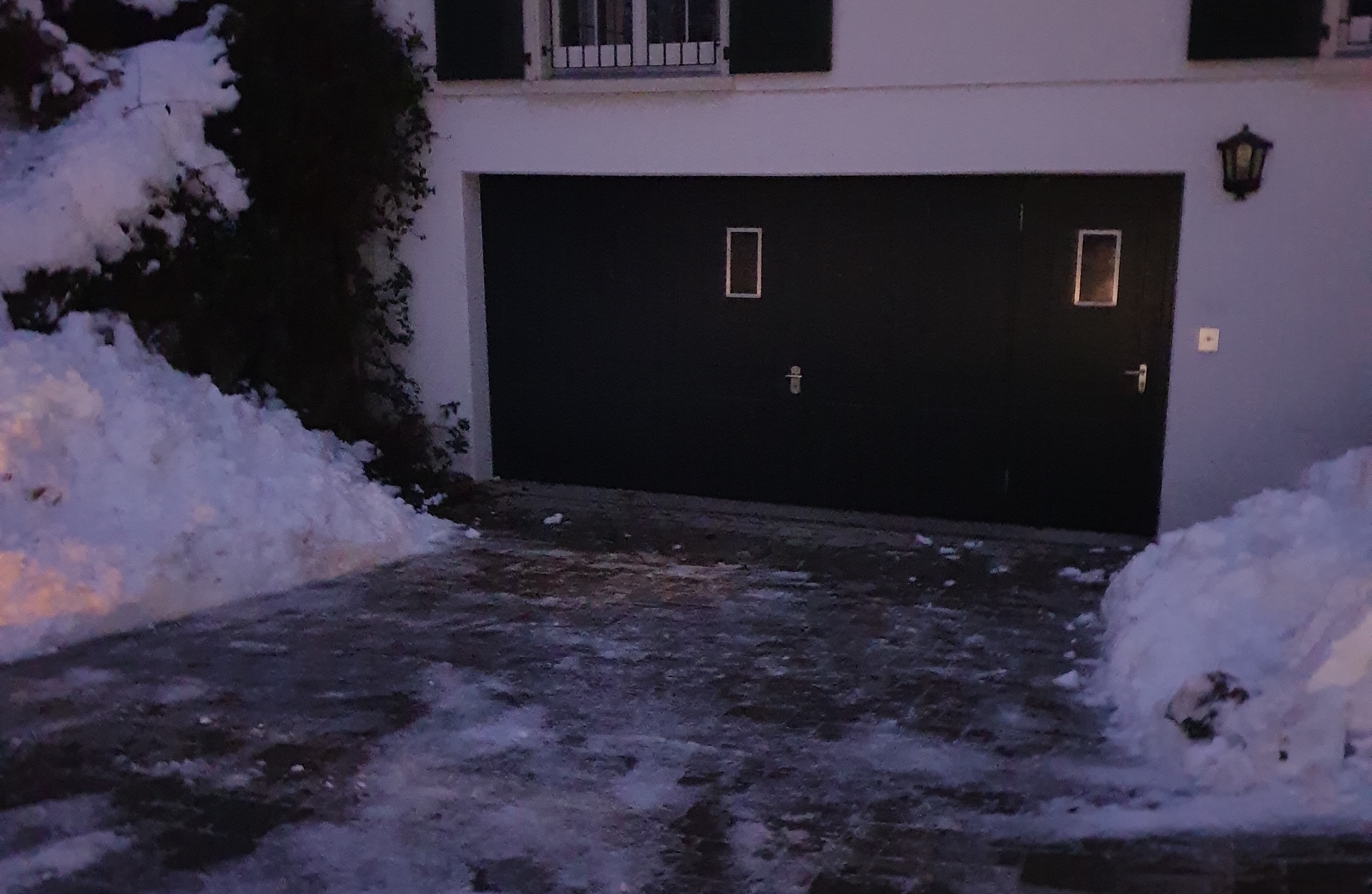 Geräumte und gestreute Garageneinfahrt mit aufgeschobenen Schneewällen