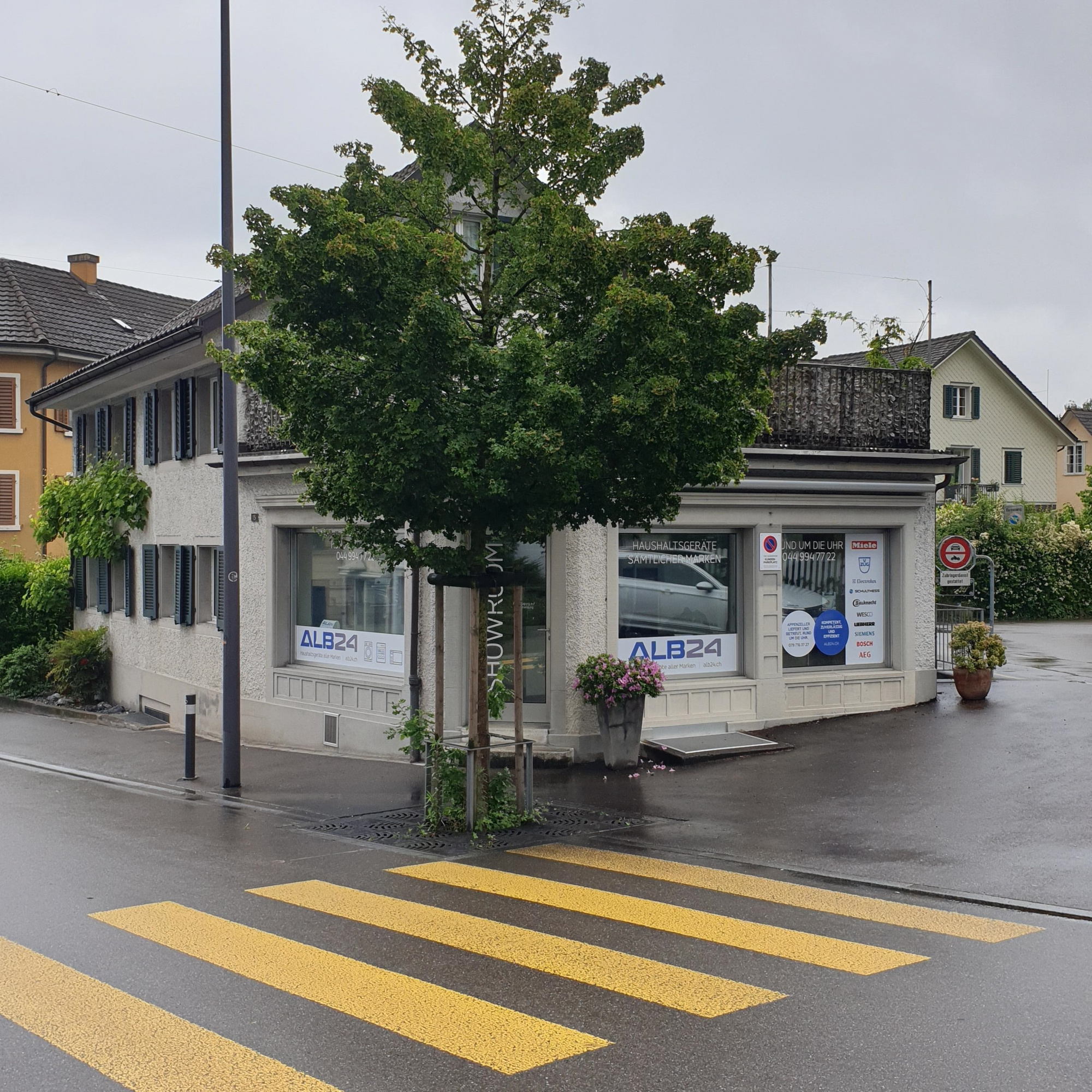Showroom der ALB24 GmbH in Männedorf: Eckgebäude an der Kugelgasse mit ALB24-Schaufensterbeschriftung und Markenlogos